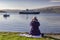 Ferry leaving Craignure port in mull with woman photographing the scene