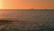 Ferry silhouette sailing ocean at dawn time. Calm water washing golden beach