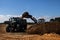 Fertilize the field, excavator with shovel fills manure in the t