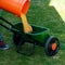 Fertilizer spreader is filled with orange product