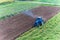 Fertilizing fields. Blue tractor fertilizing a field. Farmers spreading fertilizer with shovels