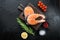 Fesh raw salmon fillet with herbs, over black background, top view with copy space