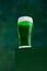 Festival drink. Glass of foamy frothy green beer over dark green background. Traditional hop taste. Concept of st