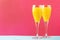 Festive alcohol cocktail mimosa with orange juice and cold dry champagne or sparkling wine in glasses, pink treandy background,