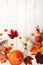 Festive autumn decor from pumpkins, berries and leaves on a white  wooden background. Concept of Thanksgiving day or Halloween.