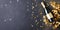 Festive background with champagne glass, gold confetti stars and party ribbons on a dark background.