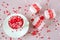 Festive background. Coffee cup, full of multicolor sweet sprinkles sugar candy hearts and packing Valentine`s Day gifts.