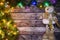 Festive Christmas background of dark old wooden boards, fir-tree, snowman and luminous garland with colored lights and Christmas b