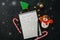 Festive Christmas background, white page of notepad with inscription, candy canes, snowman, stars on a black stone background. To