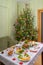 Festive Christmas served table against beautiful green pine tree decorated with many colorful new year toys. Xmas dinner,