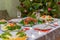 Festive Christmas served table against beautiful green pine tree decorated with many colorful new year toys. Xmas dinner,