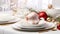 a festive Christmas table setting arranged on a white wooden table, featuring elegant dinnerware, holiday decorations