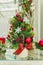 Festive chritms interior composition. Branches of fir tree and red berries decorated with cones, baubles and bows in white pot