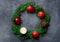 Festive colorful botanical Christmas wreath. Fresh green juniper red apples pomegranates pine cones ball candle gift box