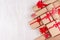 Festive craft paper gifts with red bows closeup on soft white wood board, top view, border.