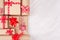 Festive craft paper gifts with red bows closeup on soft white wood board, top view, border.