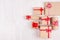 Festive craft paper gifts with red bows on soft white wood board, top view, border.