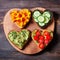 Festive delicious bread toasts with various vegetables, heart-shaped, on a wooden board