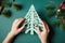 Festive DIY: woman crafting a paper tree for the holidays, top view