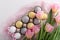 Festive Easter composition of Easter eggs, tulips, rabbit paws on white background