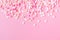 Festive frame made of colorful pastel sprinkles on a pink background, copy space on top. Sprinkle sugar with balls and stars,
