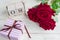 A festive gift, a wooden calendar, bouquet of red roses and a gift box on a wooden background. The concept of congratulations on