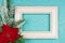 Festive greeting card for Christmas with photo frame, spruce tree branch and poinsettia on blue confetti background