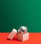 Festive inspired concept. Open gift disposable white box. Shiny disco ball inside it. Creative copy space with green and red