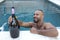 Festive man holding large champagne bottle in pool party