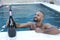 Festive man holding large champagne bottle in pool party