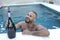Festive man holding large champagne bottle in pool party