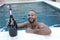 Festive man holding large champagne bottle in pool party