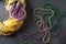 A festive Mardi Gras King Cake in gold, green and purple with colored beads on a gray slate surface