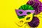 Festive Mardi Gras masquerade yellow background. Fat Tuesday carnival, masks, beads, traditional decor