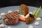 Festive menu dish with roasted veal, morels, vegetables and a fried potato stuffed with onion seeds on a blue gray plate