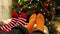 Festive mood. Close-up of two pairs of legs in knitted socks next to the Christmas tree.