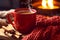 Festive mug by the fireside, Hot drink in a red knitted mitten