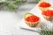 Festive new year appetizer tartlets stuffed with red caviar and a slice of lime on white background with fir branches