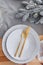 Festive New Years table setting top view, with white wavy plates, gold cutlery. Fashionable interior