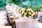 Festive outdoor wedding celebration table covered with natural tablecloth and beautifully neatly served with sets of dishes,