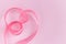 Festive pink satin silk ribbon waves in heart shape on pink background