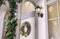 Festive porch entrance door way with lantern and decorative wreath on white facade Christmas holidays