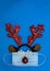 Festive reindeer antlers with face mask and ornaments on blue paper background