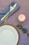 Festive Romantic Table Setting White Plate Rattan Coaster Cutlery Blue Napkin Lilac Tablecloth Lit Candle Eucalyptus Branch