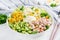Festive salad with ham, cucumber, boiled eggs, sweet corn and mayonnaise