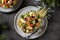 Festive salad of shrimp, kiwi, olives, soft cheese, quail eggs, cherry tomato in pineapple plates. Christmas background.