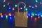 Festive season shopping concept bag with multicolour Christmas string lights bokeh