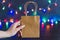 Festive season shopping concept bag with multicolour Christmas string lights bokeh