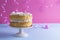 A festive sponge cake with white cream for a birthday, on a pink and blue background. Food for the holiday. Advertising poster and