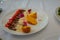 Festive table with appetizers. Plate with bread, meat, tomatoes and cheese decorated with edible clover or carnation flowers,